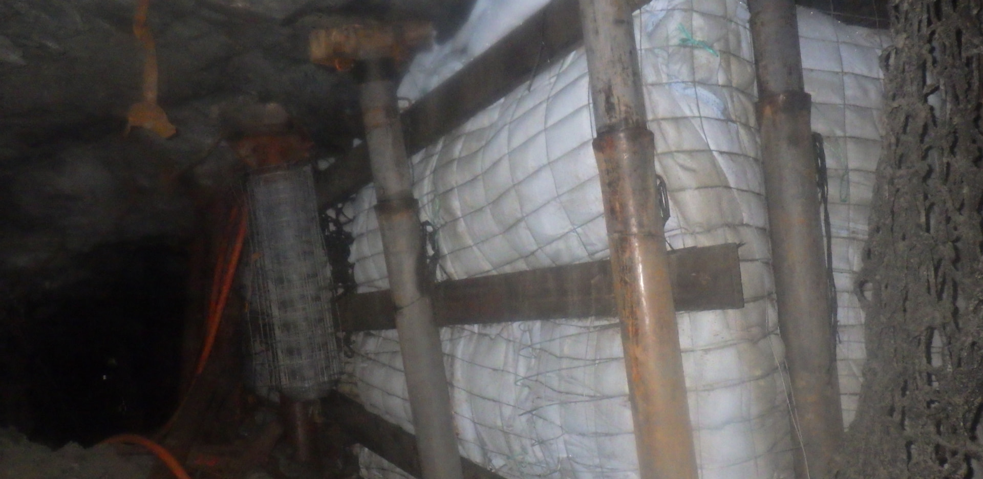 Backfill Contracting: Timber bracing and props. Horizontal timber members, steel props and wire mesh along the backfill fabric during preparation of the underground backfill line.